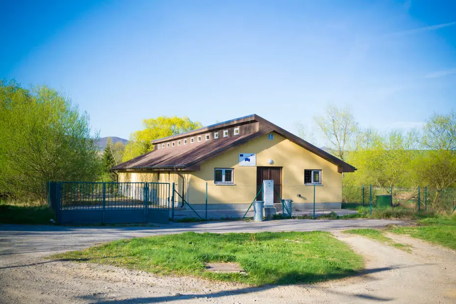 Prevádzková budova s vjazdom a parkovacou plochou.